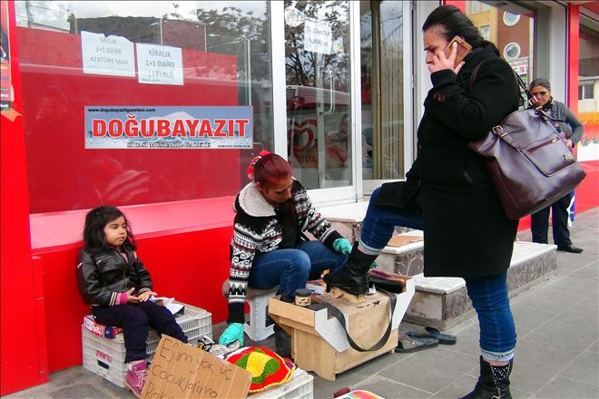 Çocukları için ayakkabı boyuyor